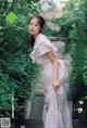 a woman in a white dress standing in front of a tree