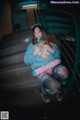 A woman sitting on the stairs holding a pink toy gun.