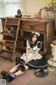 A woman in a maid outfit sitting on the floor.