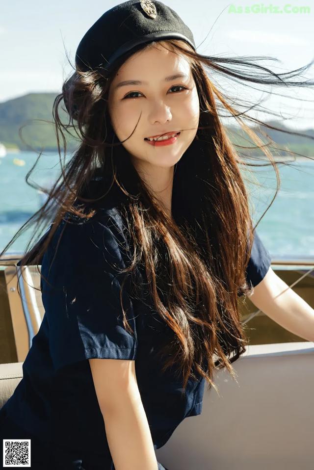 A woman with long brown hair wearing a black hat.
