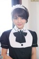 A woman in a black and white maid outfit posing for a picture.