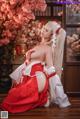 A woman in a red and white kimono sitting on a wooden floor.