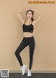 A woman in a black sports bra top and black leggings.