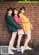 A group of three young women standing next to a brick wall.