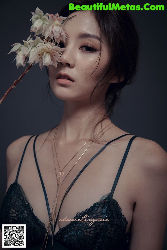 A woman in a black lingerie holding a flower in her hand.