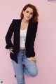 A woman in a black blazer and jeans posing for a picture.