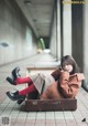 A woman sitting on top of a brown suitcase.