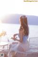 A woman sitting on a white chair by the water.