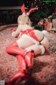 A woman in a red and white outfit laying on a rug.